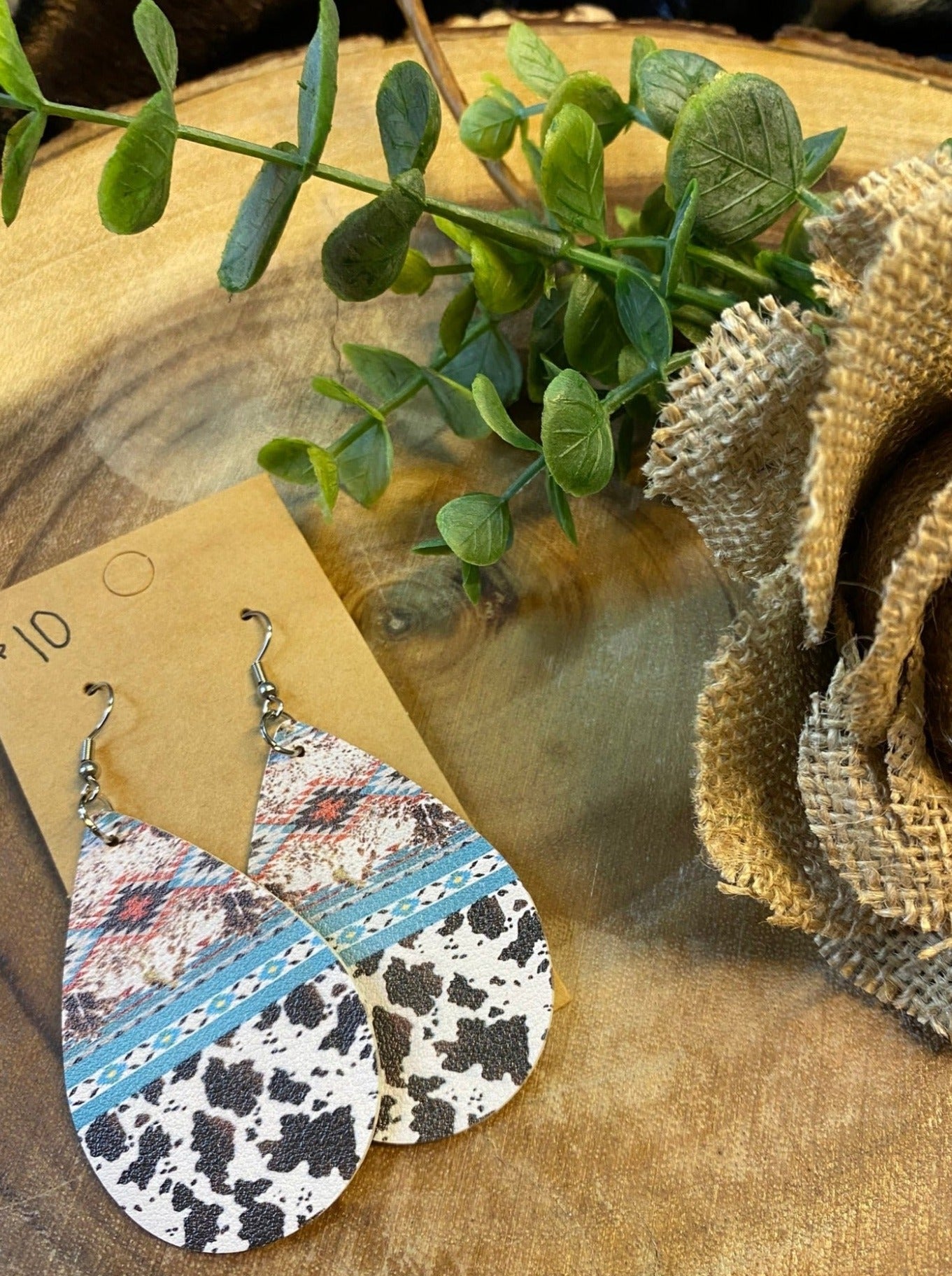 brown turquoise terracotta Aztec print with turquoise stripe with cow print on bottom half of teardrop leather earring  